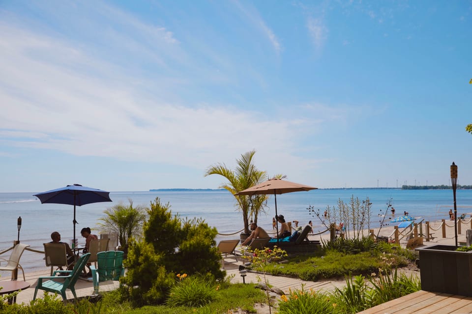 The rope-railed timber deck with palms and umbrellas at the beach edge