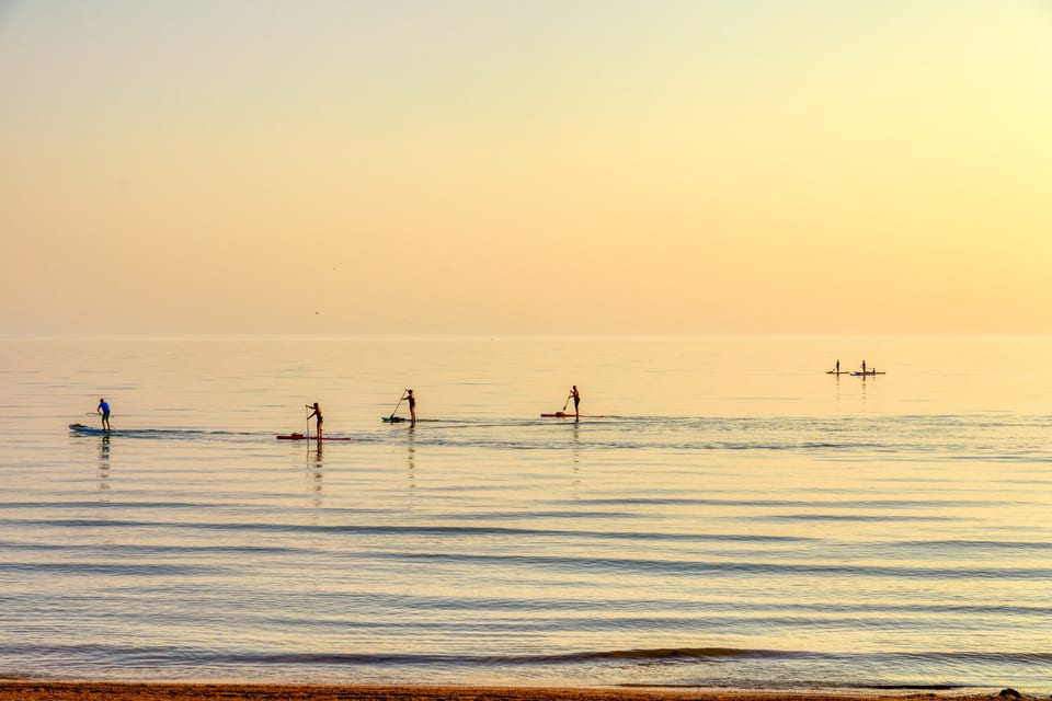 Paddle boarding along the shoreline at sunset near The Long Beach Resort